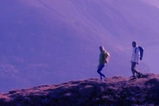 Two people walking over mountain